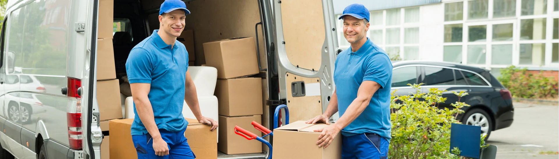 Movers loading packed boxes and furniture into a van